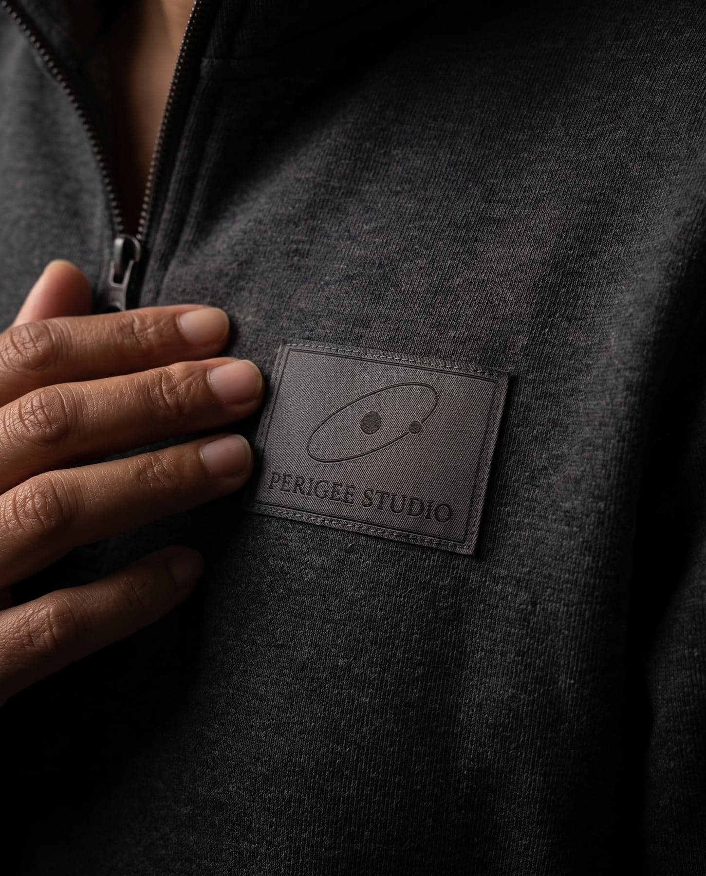 Le marquage — Just Hoods Sophomore 1/4 Zip Sweat Charcoal, écusson tissé au cœur, devant