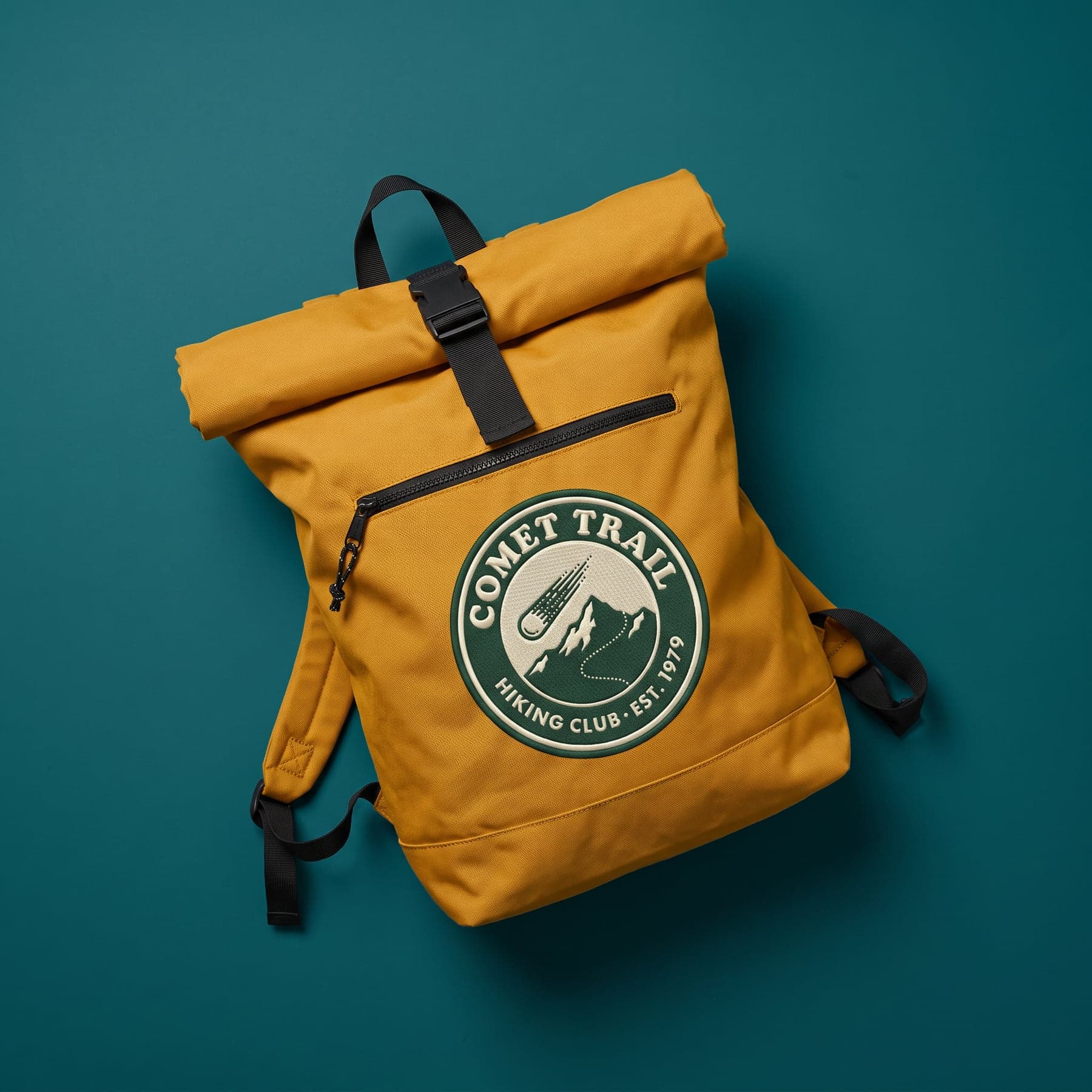 La pièce — BagBase Recycled Roll-Top Backpack Mustard, broderie sur la poitrine, devant
