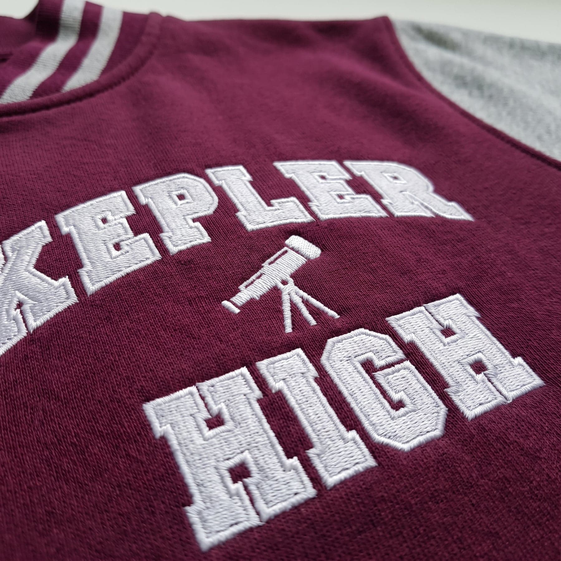 Le marquage — Just Hoods Varsity Jacket Burgundy/Heather Grey, broderie au cœur, devant